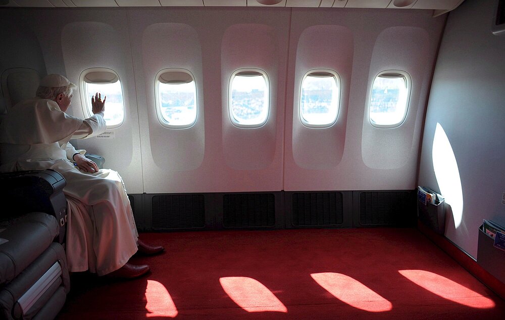 Papst Benedikt XVI. sitz im Flieger und winkt zum Fenster raus.