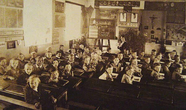 Ein Klassenfoto der ersten (links) und zweiten Klasse von Marktl am Inn, in der auch der heutige Papst Benedikt XVI unterrichtet wurde (Foto aus dem Jahr 1934). Der damals siebenjährige Joseph Ratzinger sitzt in der rechten Hälfte, dritte Reihe, als zweiter von rechts. 